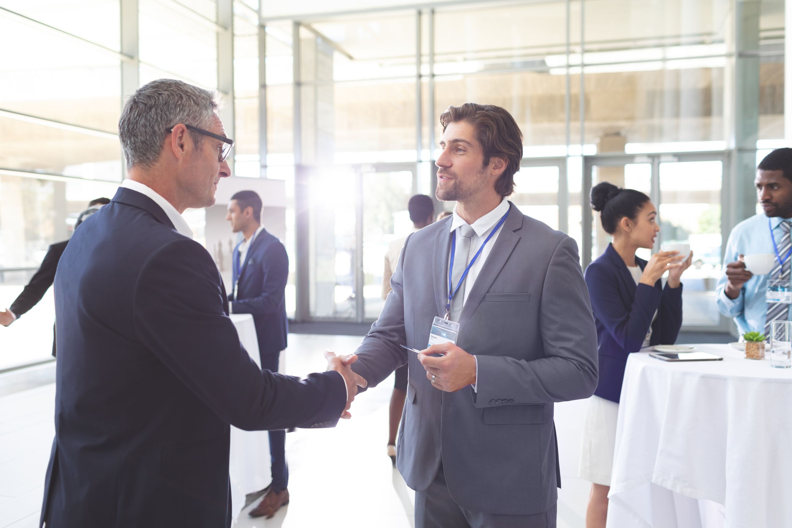 Side view of caucasian happy business people shaking hand during a seminar. Diverse business people are interacting behind them